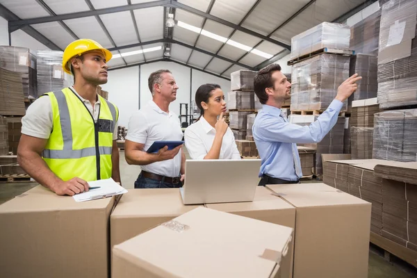 Warehouse manager pointing something to colleagues — Stock Photo, Image