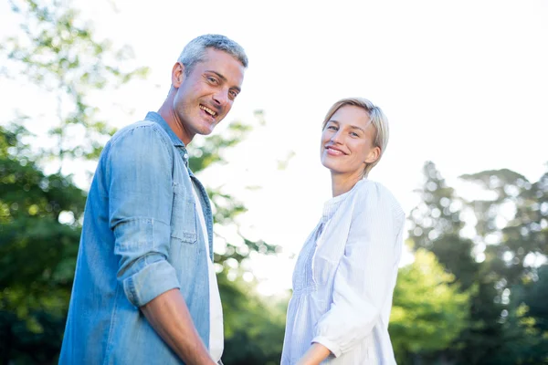 Happy couple smiling at the camera in the park — Stock Photo, Image