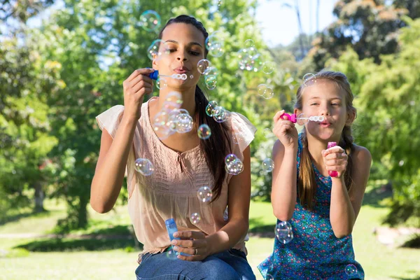 Lycklig mor och dotter blåser bubblor — Stockfoto