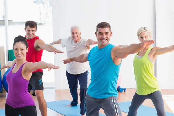 People doing warrior pose in yoga class — Stock Photo, Image