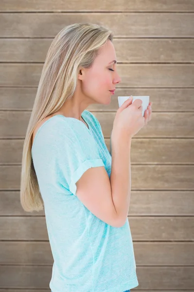 Blonde standing and holding hot beverage — Stock Photo, Image
