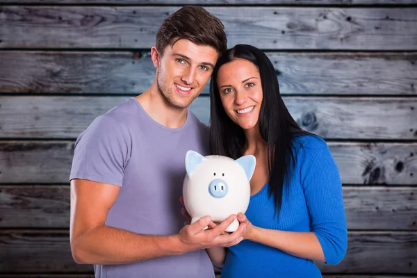 Casal segurando um banco porquinho — Fotografia de Stock