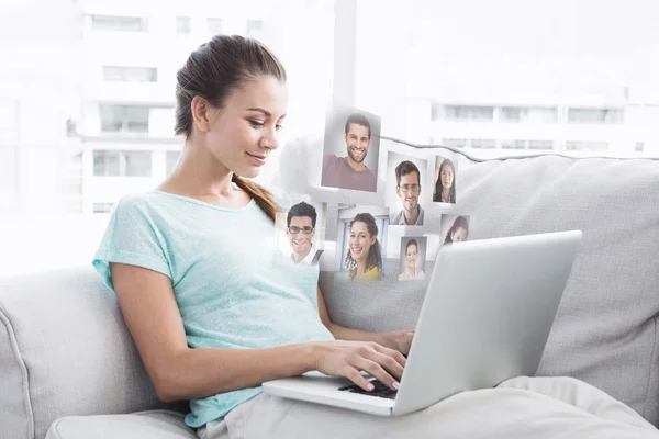 Happy woman sitting on couch using her laptop — Stock Photo, Image