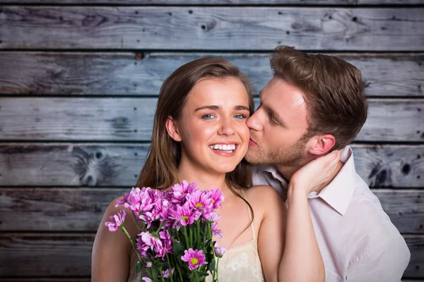 Homem beijando mulher como ela detém flores — Fotografia de Stock