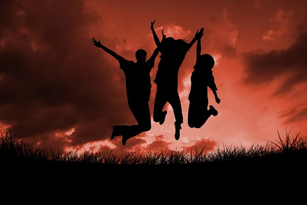 Silhouettes of people jumping against red sky — Stock Photo, Image
