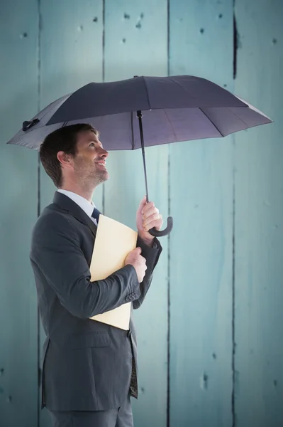 Businessman holding a file under umbrella — Stock Photo, Image