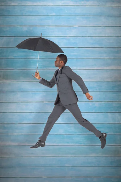 Businessman walking and holding umbrella — Stock Photo, Image