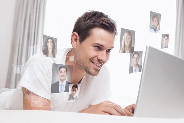 Relaxed casual man using laptop in bed — Stock Photo, Image