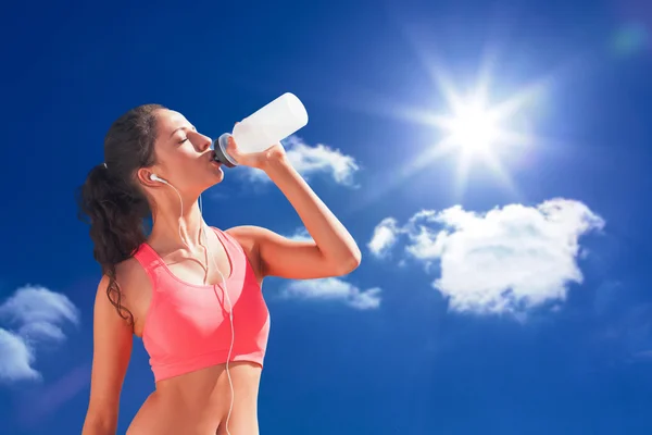 Sunn kvinne drikker vann mot himmelen – stockfoto