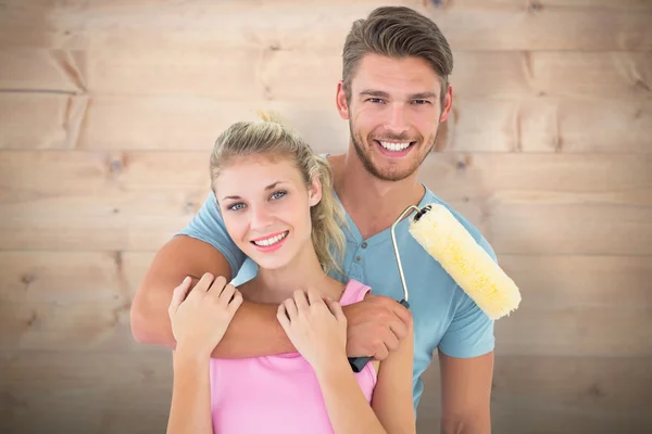 Casal abraçando e segurando rolo de pintura — Fotografia de Stock