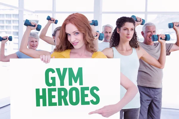 Redhead showing a poster against gym heroes — Stock Photo, Image