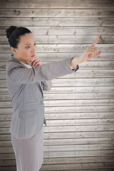 Unsmiling thinking asian businesswoman pointing — Stock Photo, Image