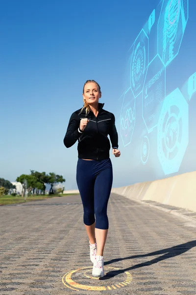 Blondin jogging på piren mot fitness-gränssnittet — Stockfoto