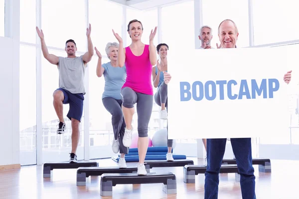 Mature man holding card against bootcamp — Stock Photo, Image