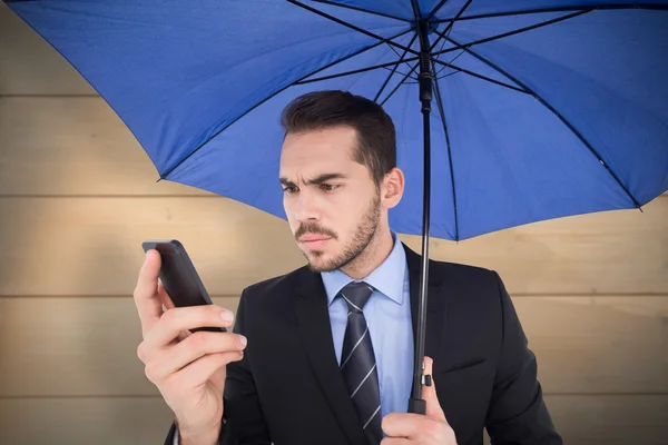 Zakenman onder paraplu via mobiele — Stockfoto