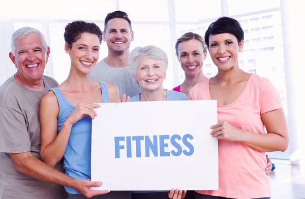 Fitness against fit people holding blank board in yoga class — Stock Photo, Image