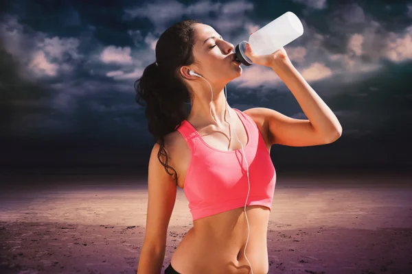 Vrouw drinkwater tegen donkere bewolkte hemel — Stockfoto