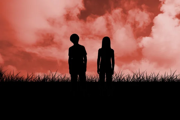 Silhuetas de duas crianças contra o céu vermelho — Fotografia de Stock