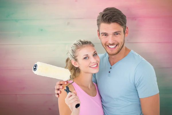 Casal abraçando e segurando rolo de pintura — Fotografia de Stock