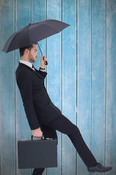 Businessman holding briefcase under umbrella — Stock Photo, Image