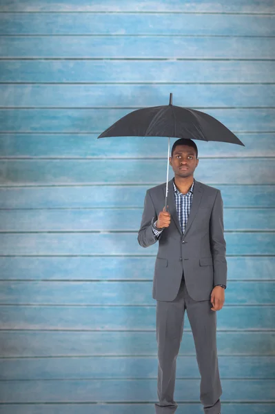 Бизнесмен, стоящий под зонтом — стоковое фото