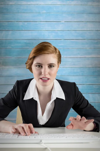 Rothaarige Geschäftsfrau sitzt am Schreibtisch und tippt — Stockfoto