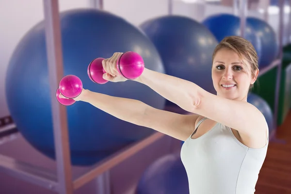 Mulher segurando pesos contra bolas de exercício — Fotografia de Stock