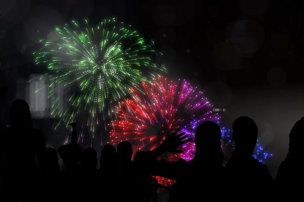 Silhouettes of cheering people against fireworks — Stock Photo, Image