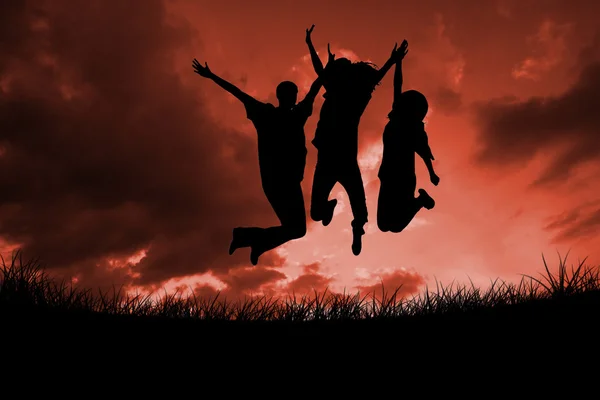 Silhouettes of people jumping against red sky — Stock Photo, Image