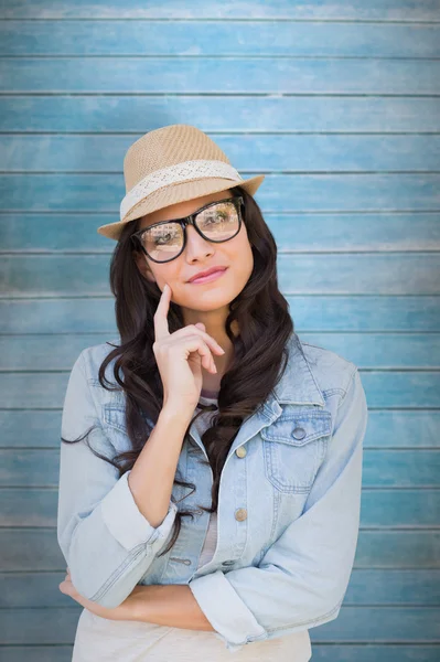 Thinking brunette against wooden planks — Stock Photo, Image