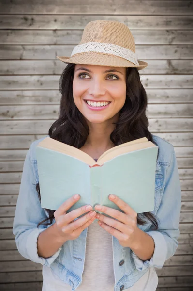 Brunette lezen tegen houten planken — Stockfoto