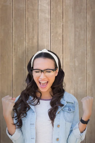 Cheering brunette against wooden surface — Stock Photo, Image