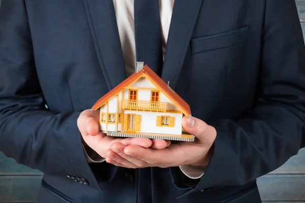 Businessman holding miniature house model — Stock Photo, Image