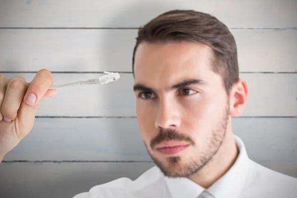 Hombre de negocios enfocado sosteniendo cable blanco — Foto de Stock