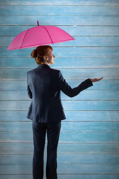 Businesswoman with umbrella against wooden planks — Stock Photo, Image