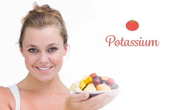 Potassium contre femme tenant une assiette de fruits — Photo