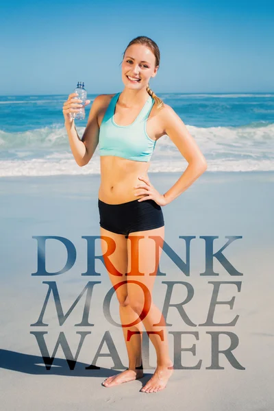 Fit mujer de pie en la playa sosteniendo el agua — Foto de Stock