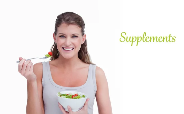 Supplements against woman eating a salad — Stock Photo, Image