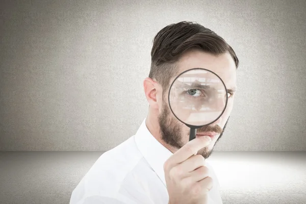 Geeky businessman looking through magnifying — Stock Photo, Image