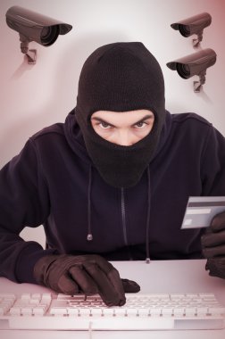 Concentrated burglar in balaclava shopping online clipart