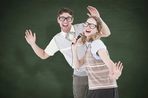 Geeky hipster couple singing into a microphon — Stock Photo, Image