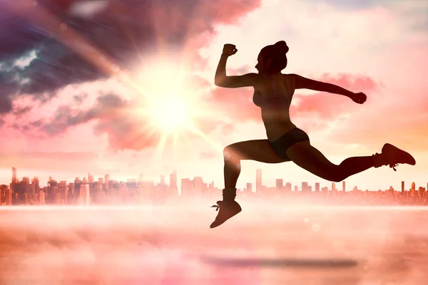 Composite image of fit brunette running and jumping — Stock Photo, Image