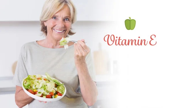 Витамин e против улыбающейся женщины, которая ест салат — стоковое фото