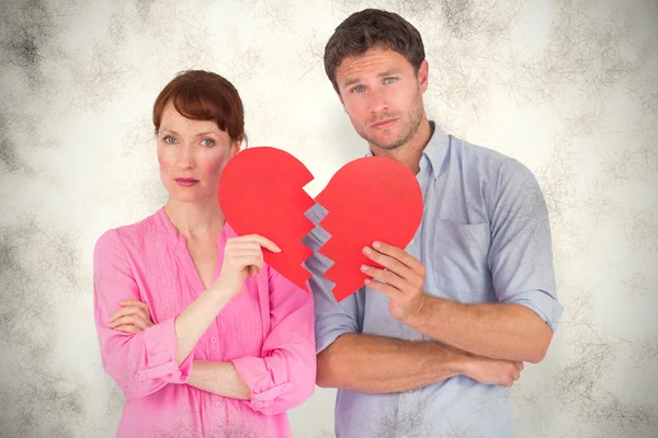 Imagen compuesta de una pareja sosteniendo un corazón roto — Foto de Stock