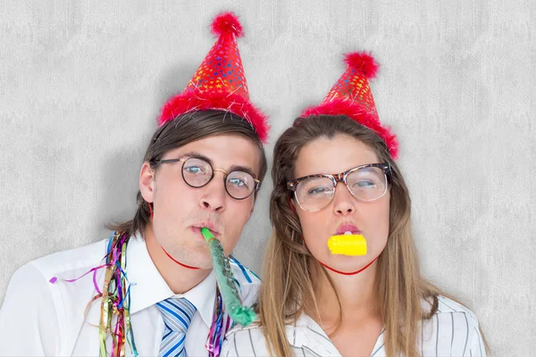 Geeky hipster wearing a party hat with blowing — Stock Photo, Image