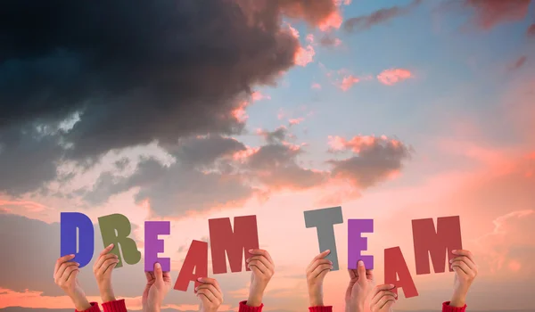 Composite image of hands holding up dream team