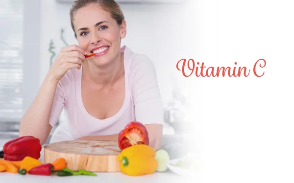 Vitamin c against cheerful woman eating vegetables — Stock Photo, Image