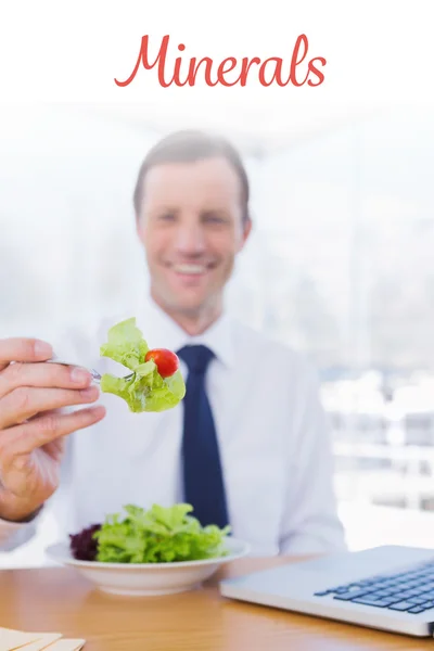 Minerals against businessman eating a salad — Stock Photo, Image