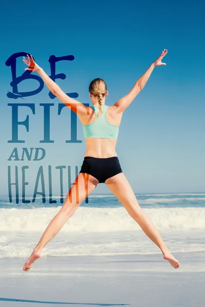 Fit vrouw springen op het strand met armen — Stockfoto