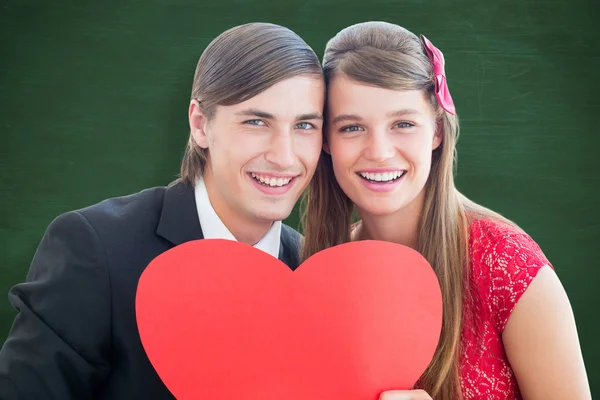 Cute geeky couple smiling and holding heart — Stock Photo, Image